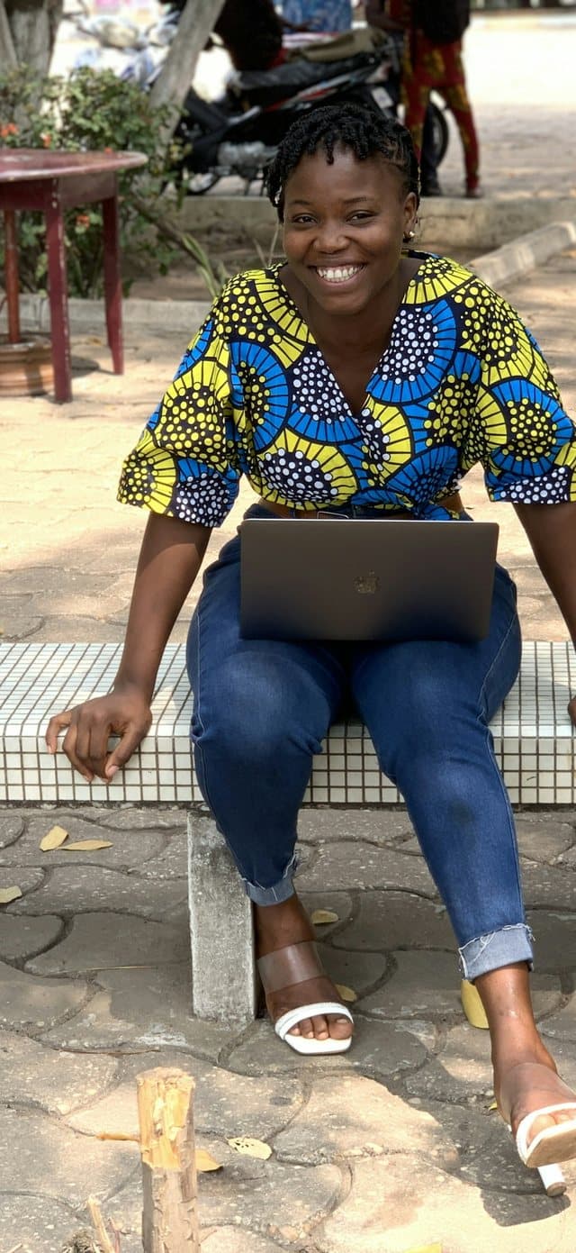 Kemi, a designer in Lagos, smiling with her laptop